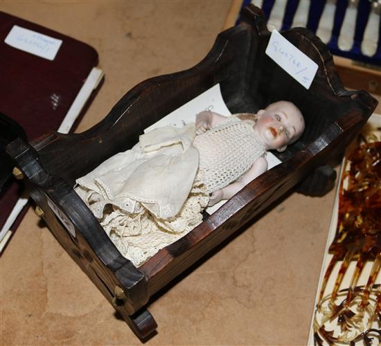 Miniature china doll in wooden cradle